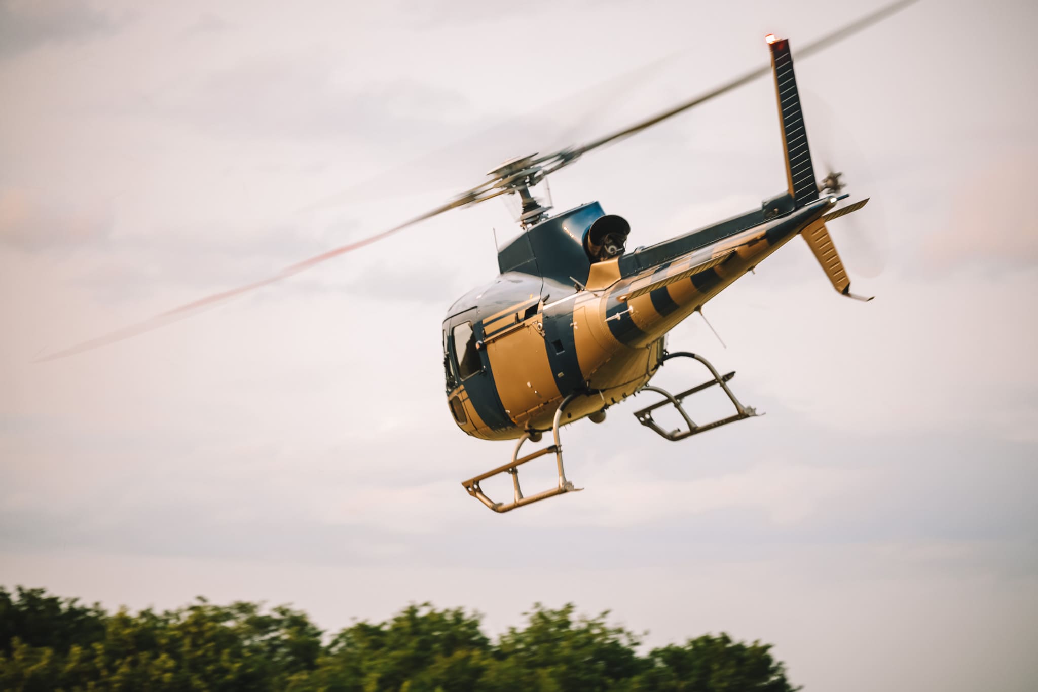 Hélicoptère jaune en vol au-dessus d'une zone rurale française